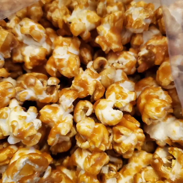 Palomitas bañadas en caramelo dorado brillante dentro de una bolsa transparente.
