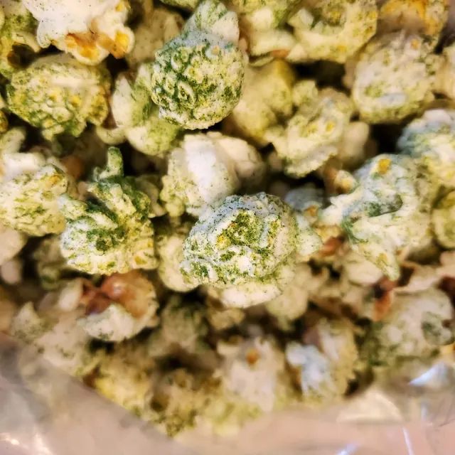 Palomitas espolvoreadas con hierbas verdes secas dentro de una bolsa transparente.
