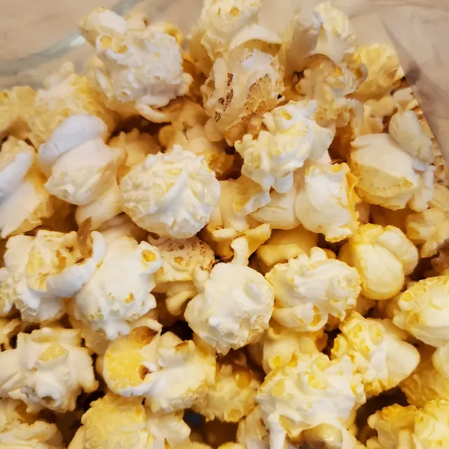 Palomitas de mantequilla doradas servidas en un tazón de vidrio.